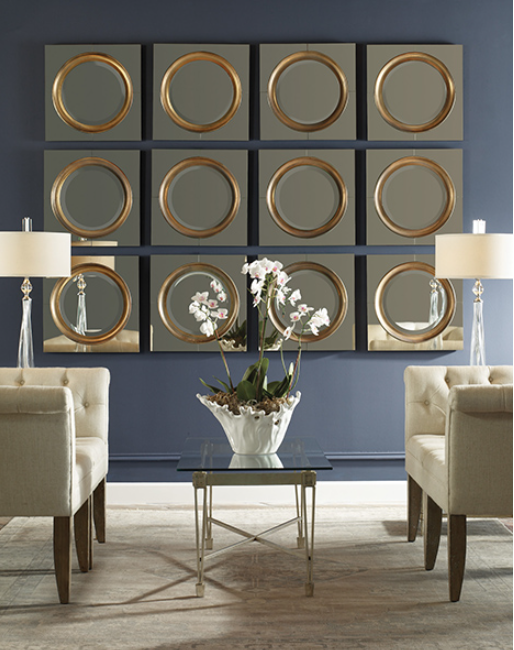 12 small square mirrors with gold circular detailing hung together on a wall in a grid style pattern