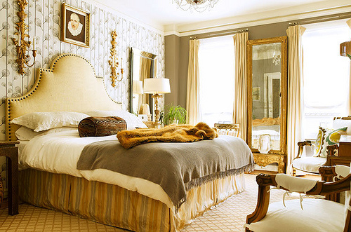 Large rectangular mirror with gold frame in bedroom between two large windows