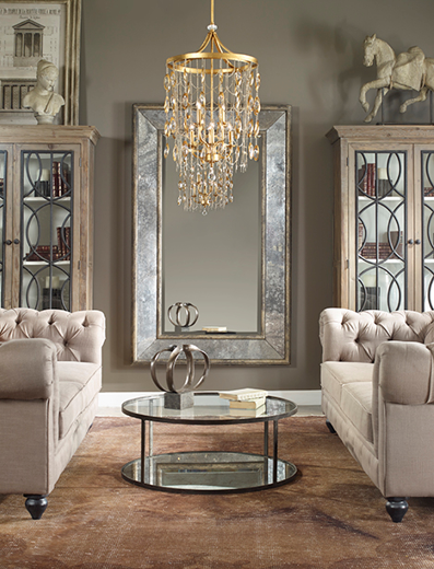 rectangular silver framed mirror on grey wall with gold chandelier hanging from ceiling