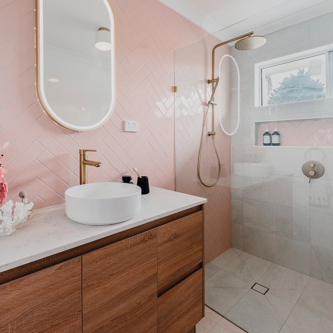 Gold Framed Oval Bathroom Mirror on Pastel Pink Bathroom Wall